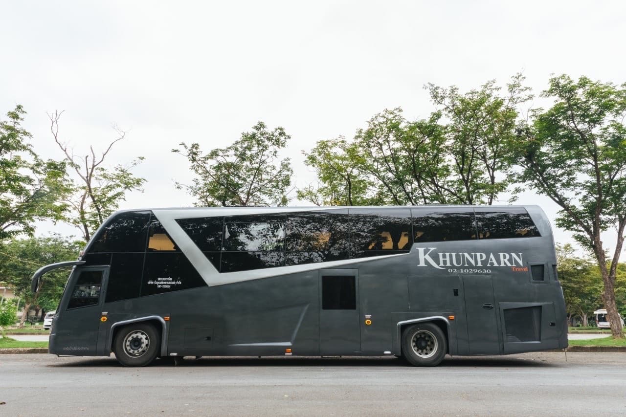 รถบัสสองชั้นสีเทาของ KHUNPARN Travel จอดด้านข้าง เห็นป้ายชื่อและเบอร์ 02-102-9630